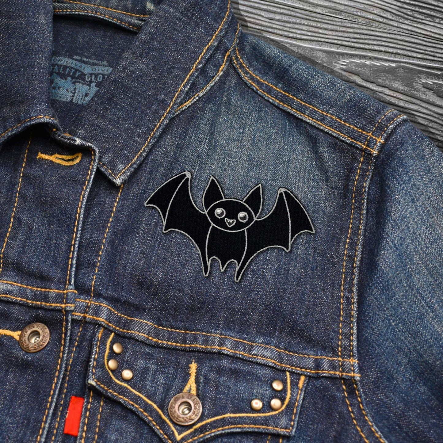 Black bat-shaped patch on a denim jacket