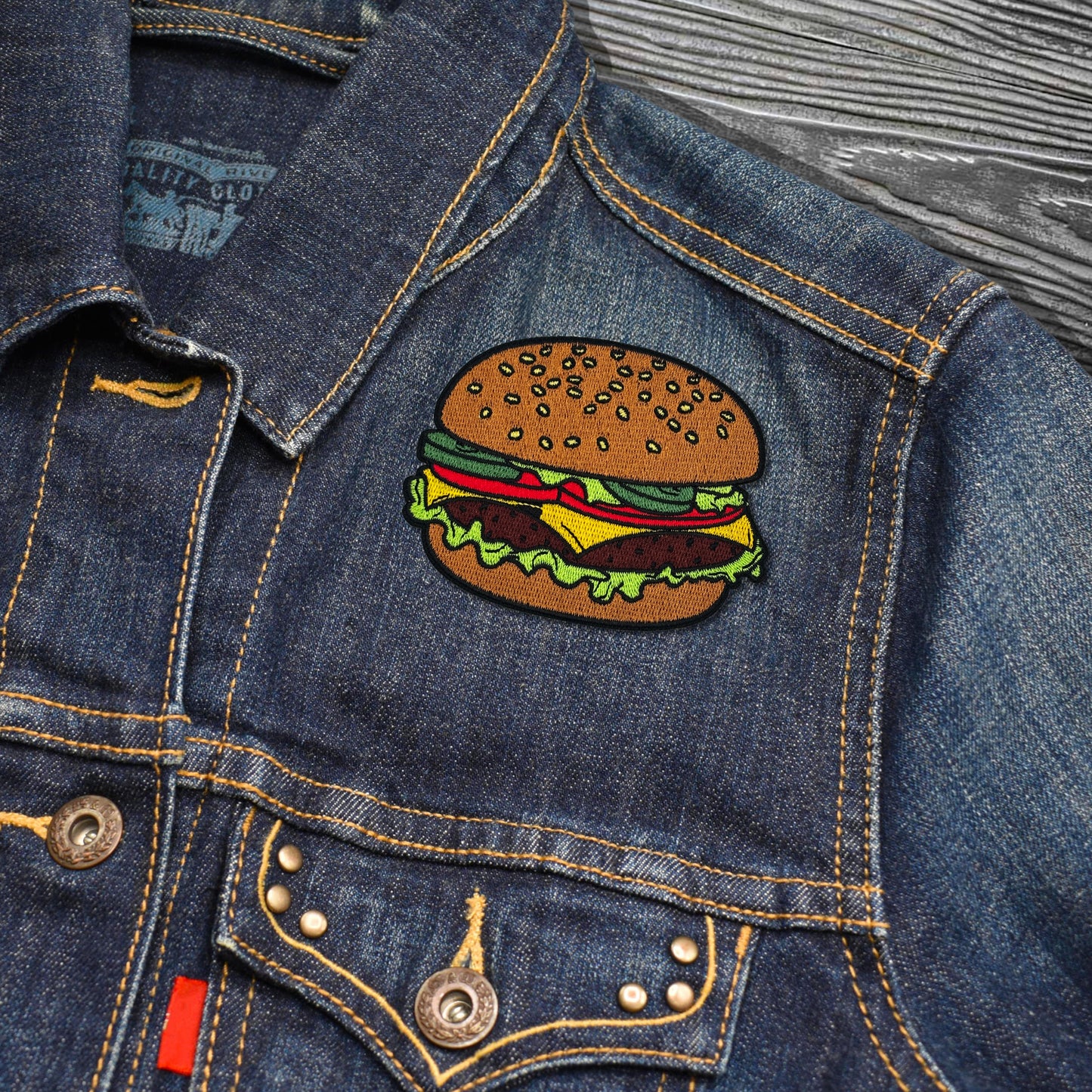 Denim jacket with a hamburger patch on a textured surface