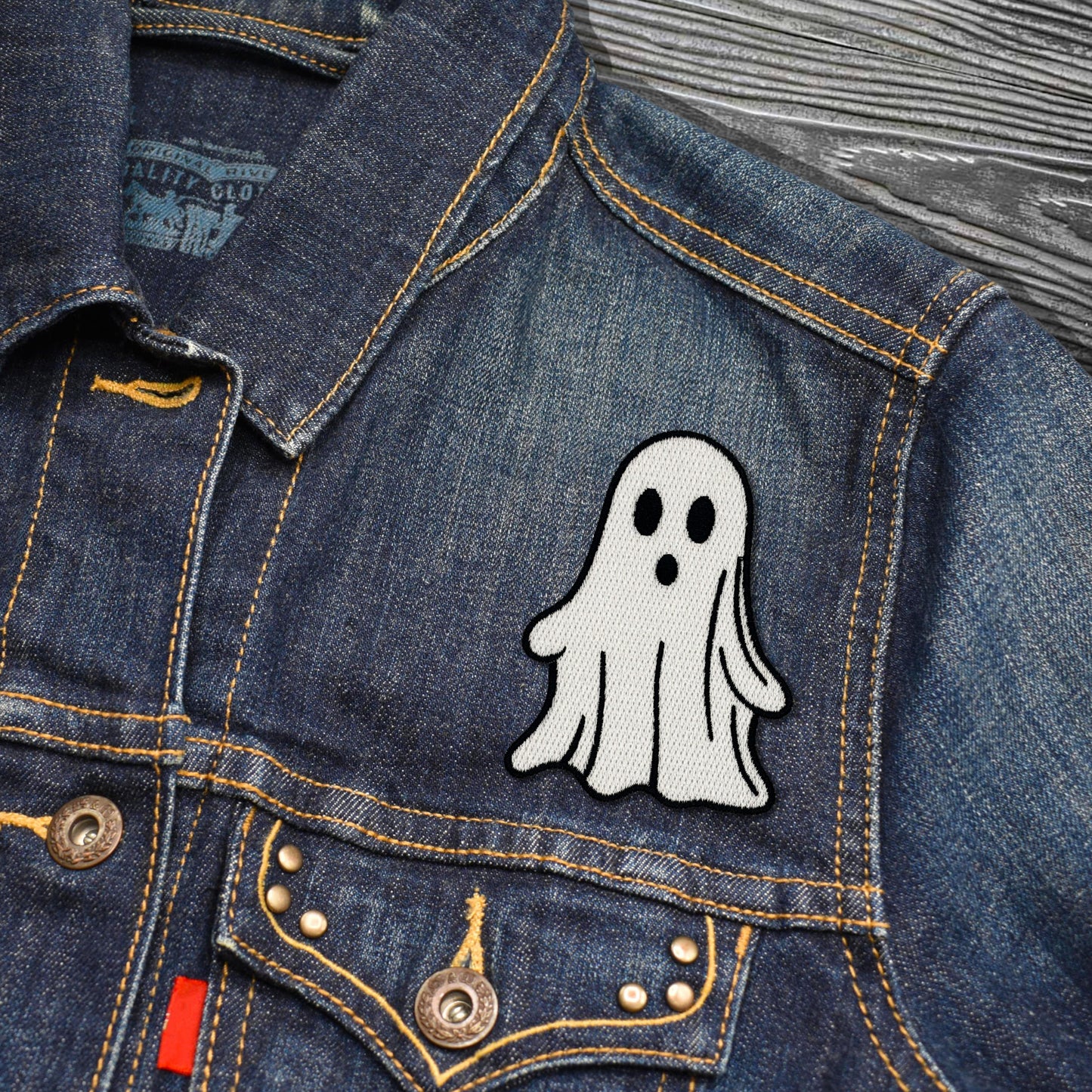 Denim jacket with a ghost patch on a wooden surface