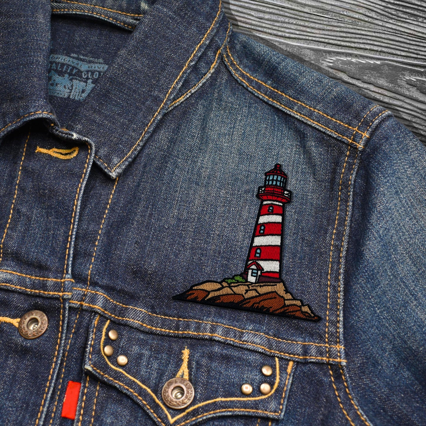 Denim jacket with a lighthouse patch on a textured surface