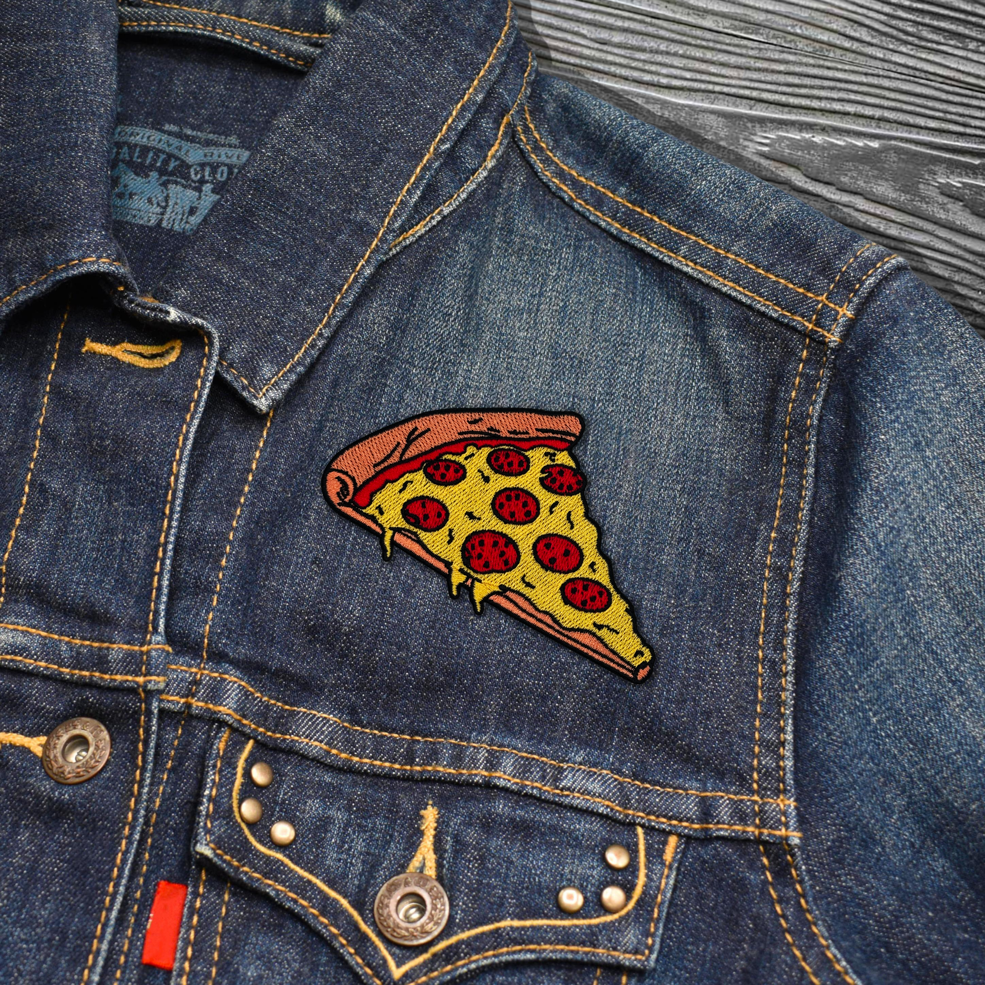 Denim jacket with a pizza slice patch on a wooden surface