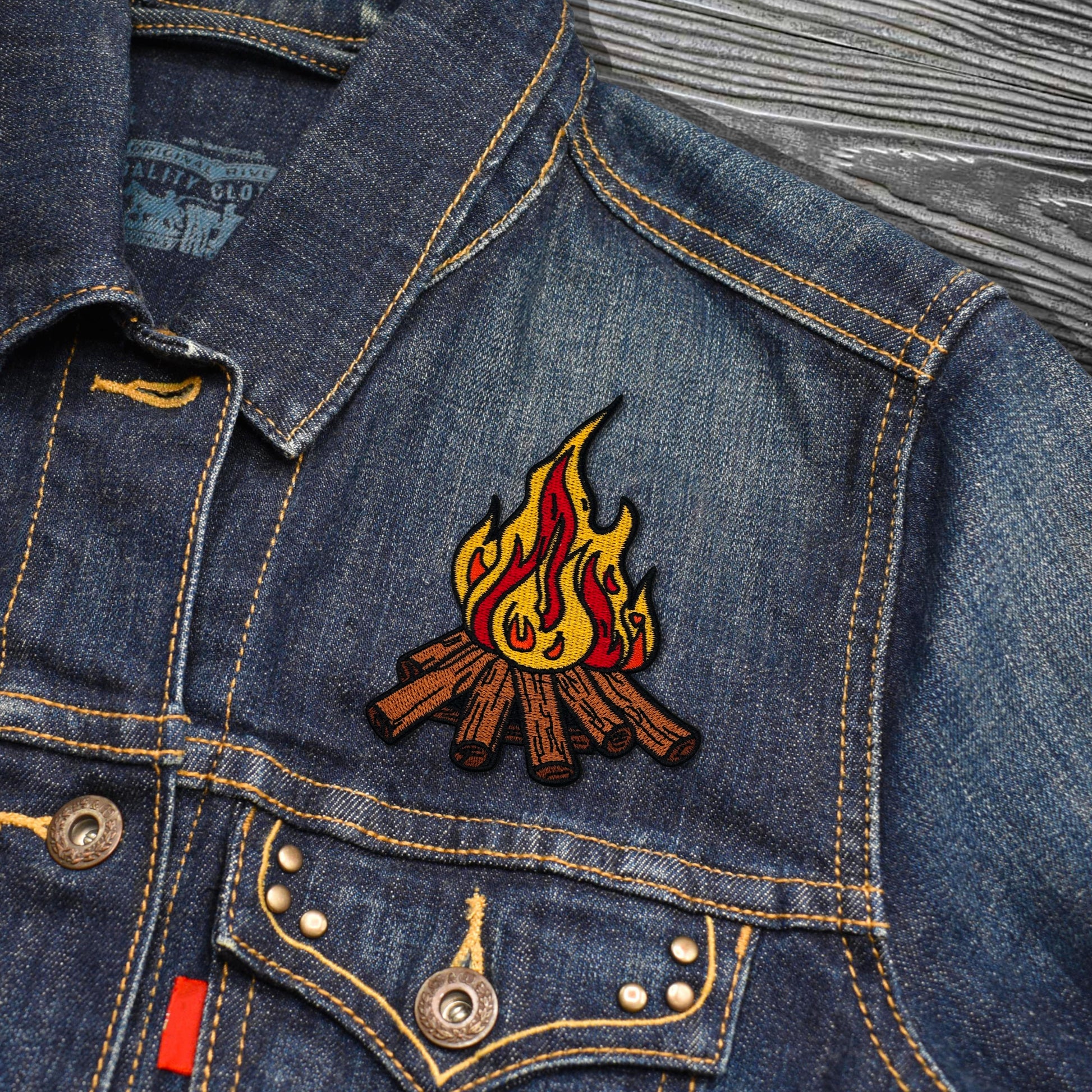 Denim jacket with a campfire patch on a textured surface