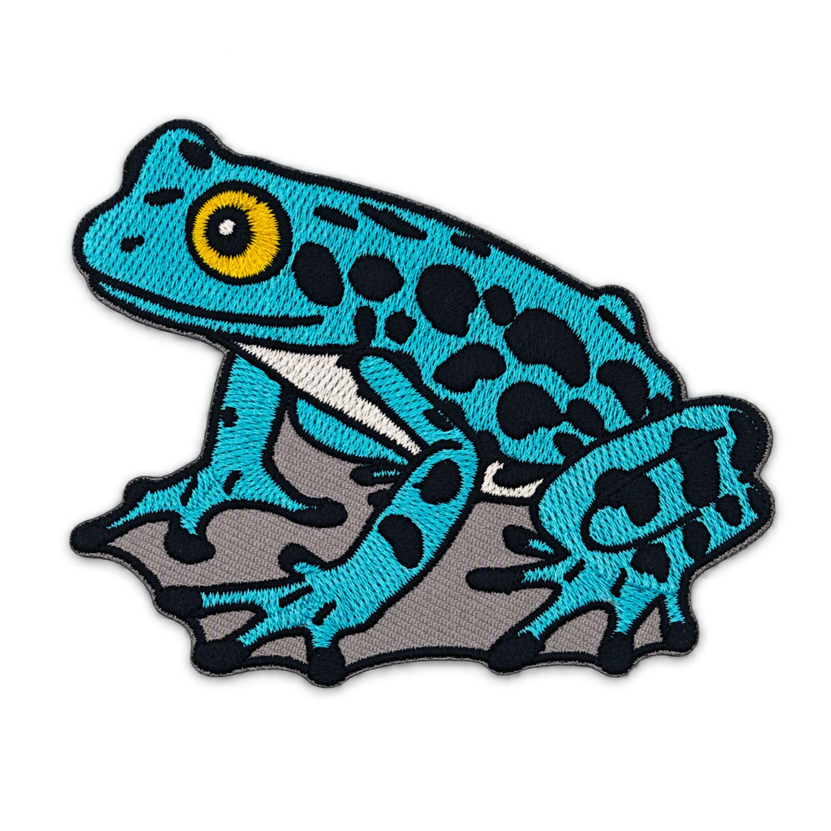 An embroidered frog patch featuring a bright turquoise blue body with black spots, a yellow eye, and a gray underside, outlined in black on a white background.