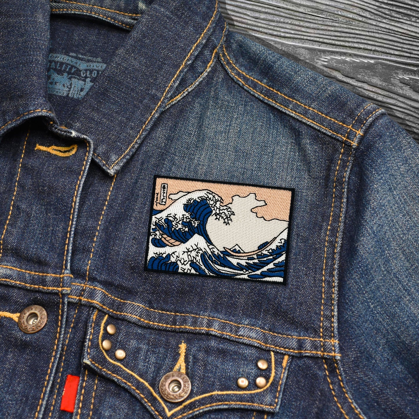 Denim jacket with Embroidered patch of The Great Wave off Kanagawa on a wooden surface